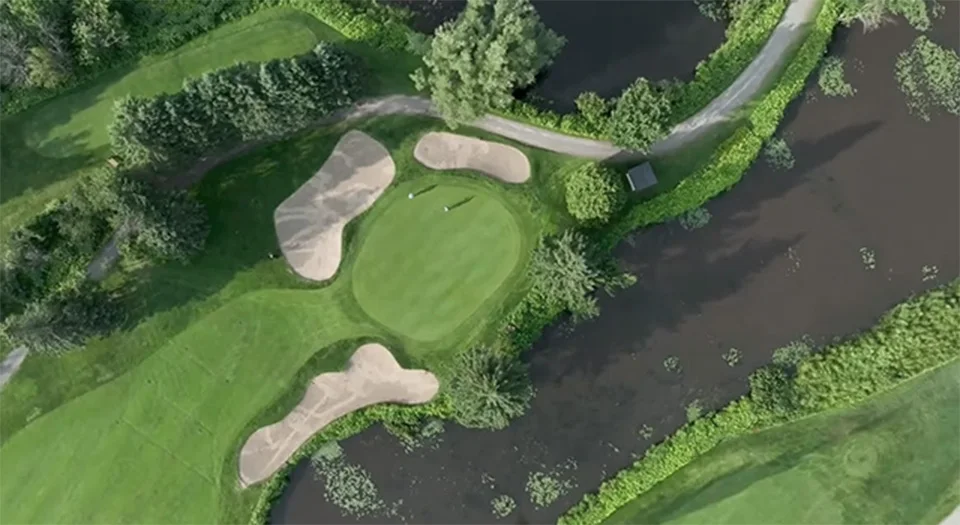 Un parcours de golf vu du ciel, au bord de la rivière.
